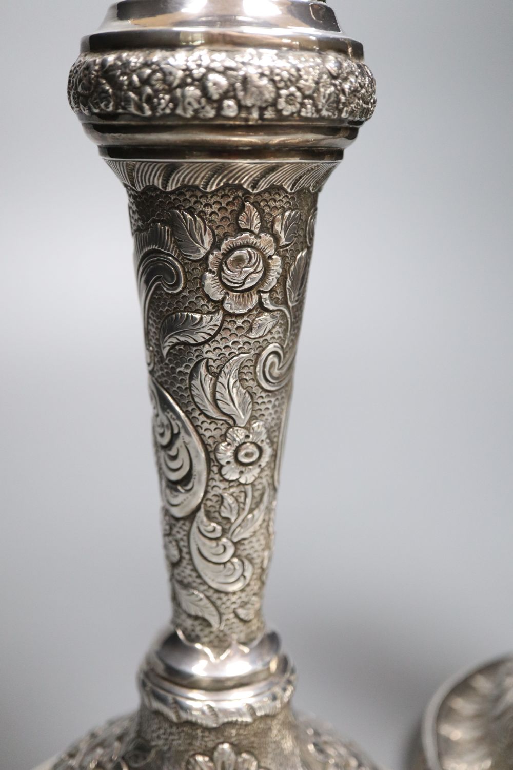 A pair of late George III silver candlesticks, with later embossed decoration, Soloman Hougham, London 1817,